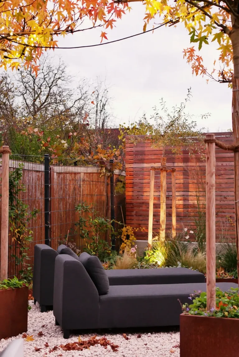 Moderne Gartenlandschaft mit zwei schwarzen Loungesofas und dekorativen Pflanzen.