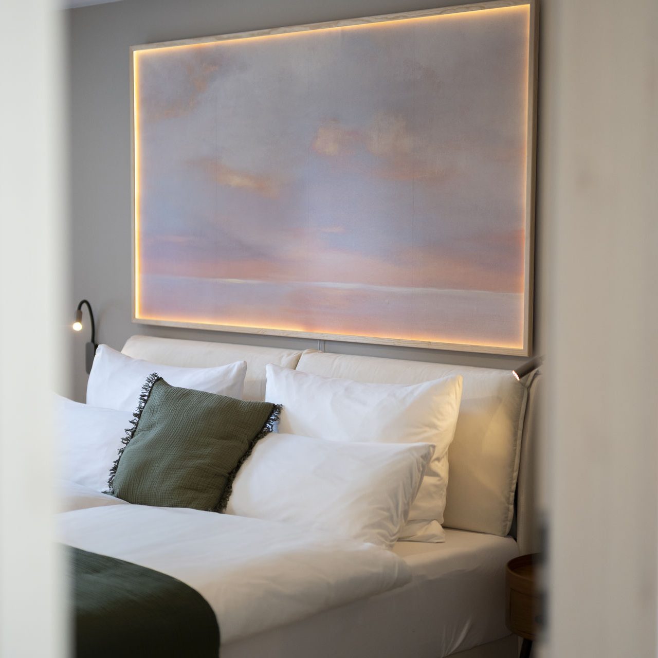 Schlafzimmer mit Doppelbett und beleuchtetem Wandbild über dem Kopfteil