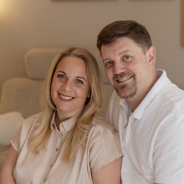 Sarah und Manuel von &oh, lächelnd nebeneinander auf einem hellen Sofa